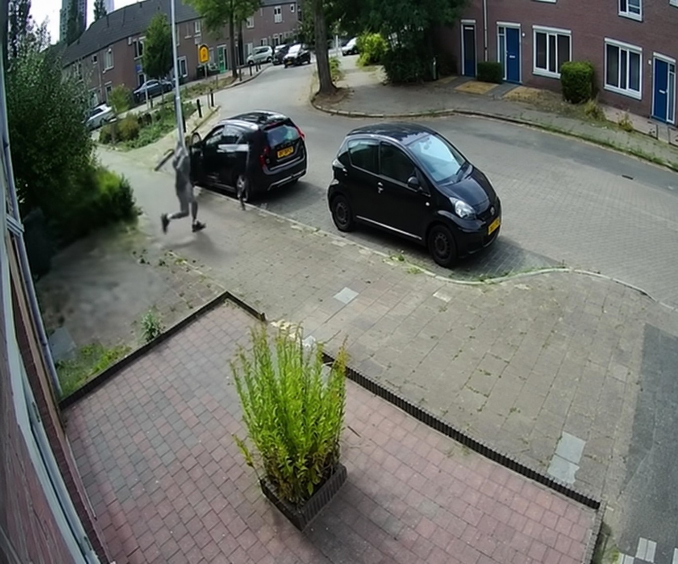 Een man rent richting personen bij een open portier van een geparkeerde auto